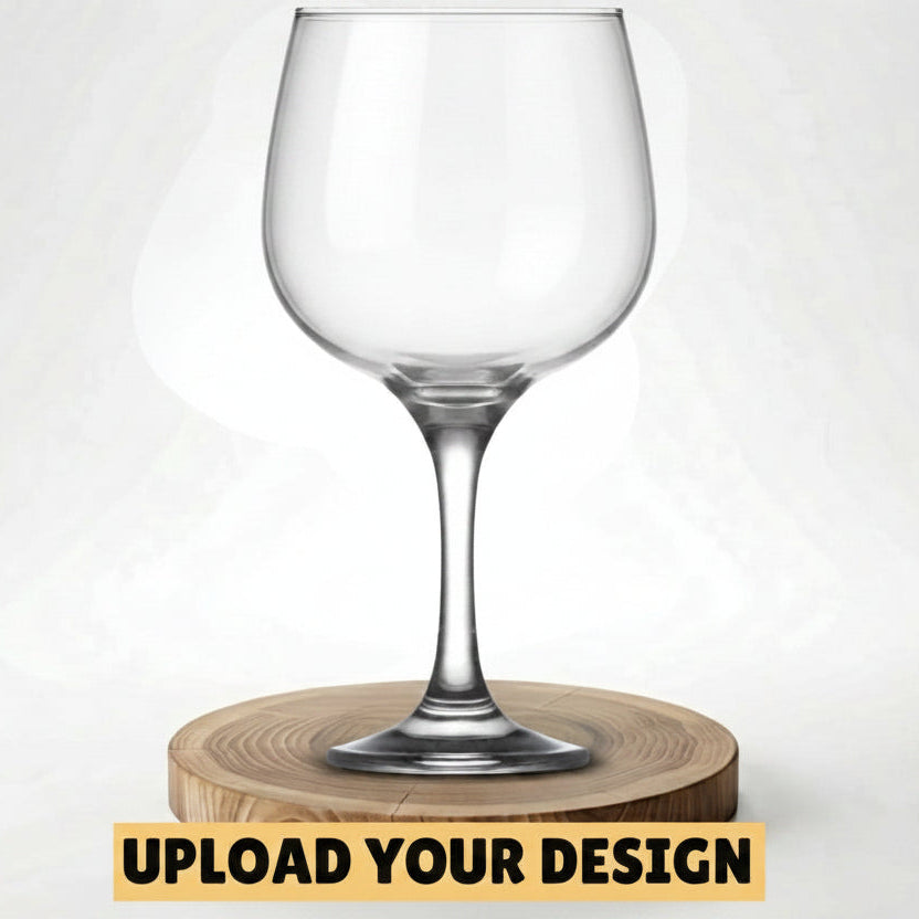 A clear stemmed wine glass with a silver Celtic knot design near the rim, displayed on a round wooden coaster against a light gray background. A yellow banner at the bottom reads 'UPLOAD YOUR DESIGN'.