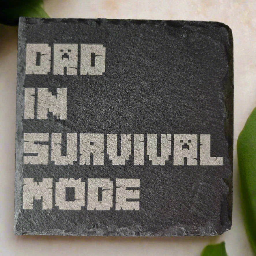 Laser engraved bamboo coaster with with “Dad in Survival Mode” printed in a blocky pixel-style gaming font inspired by Minecraft, with bold black text, novelty gift for gamer dads, Father’s Day or birthday present.