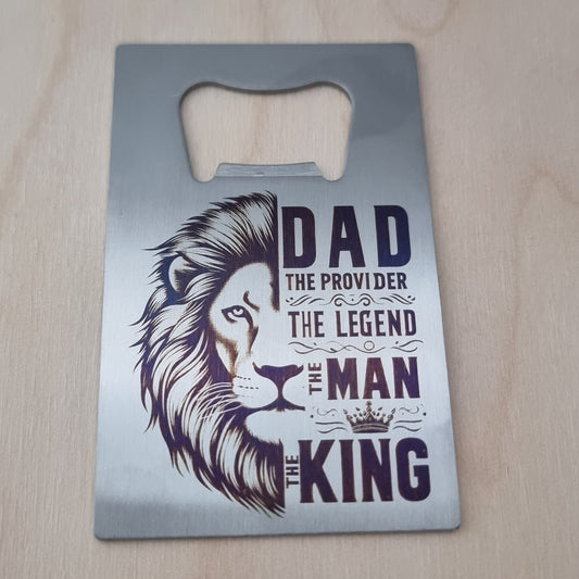 Metal bottle opener with lion design and text on a wooden surface