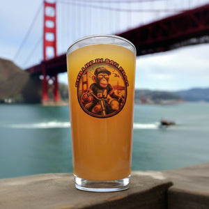 A glass of beer with a logo that includes a monkey riding a motorcycle across the Golden Gate Bridge.