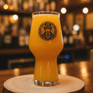 A steampunk-themed beer glass with a graphic of a man surrounded by gears, placed on a wooden surface.