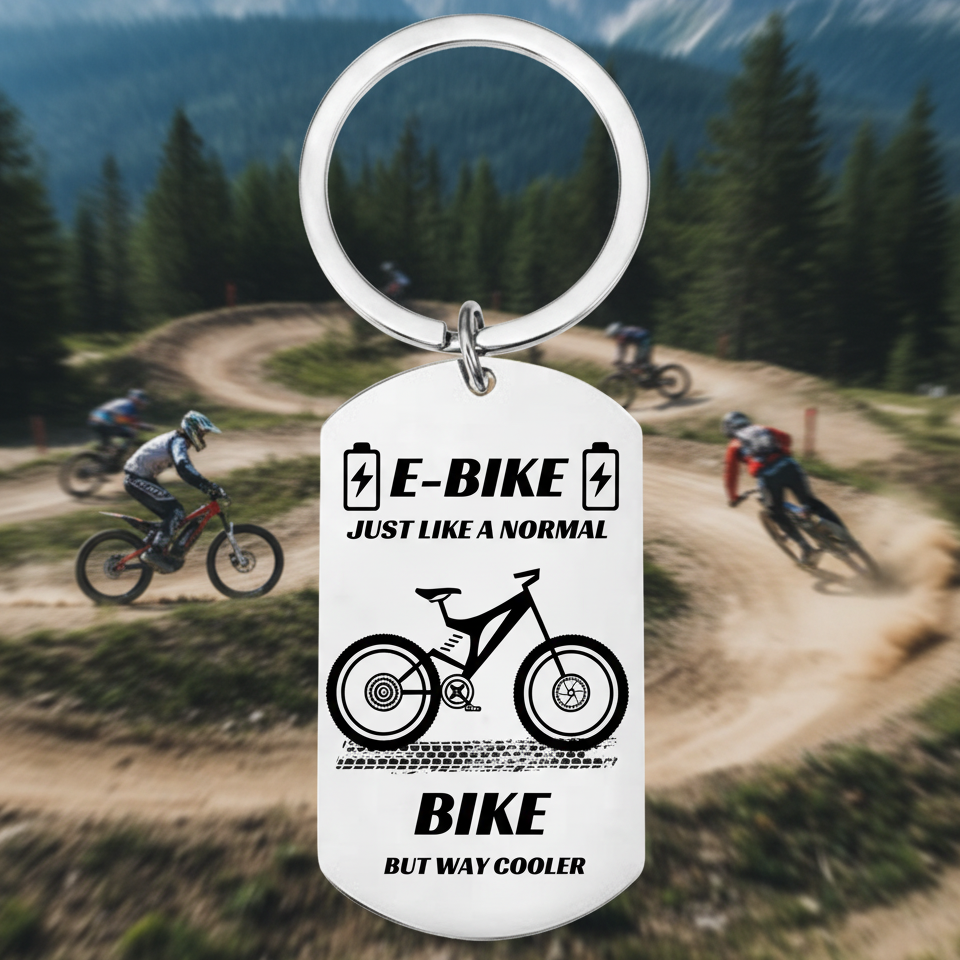 "Funny e-bike keychain with metal dog tag design, battery icons, mountain e-bike graphic and text reading just like a normal bike but way cooler"
