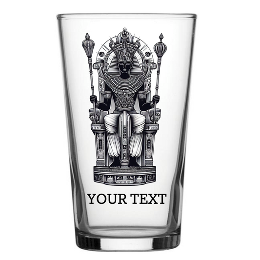 Personalised Egyptian Pharaoh pint glass featuring a detailed pharaoh seated on an ornate throne with nemes headdress, ceremonial staffs, and hieroglyphic bands, with custom text engraving at the base