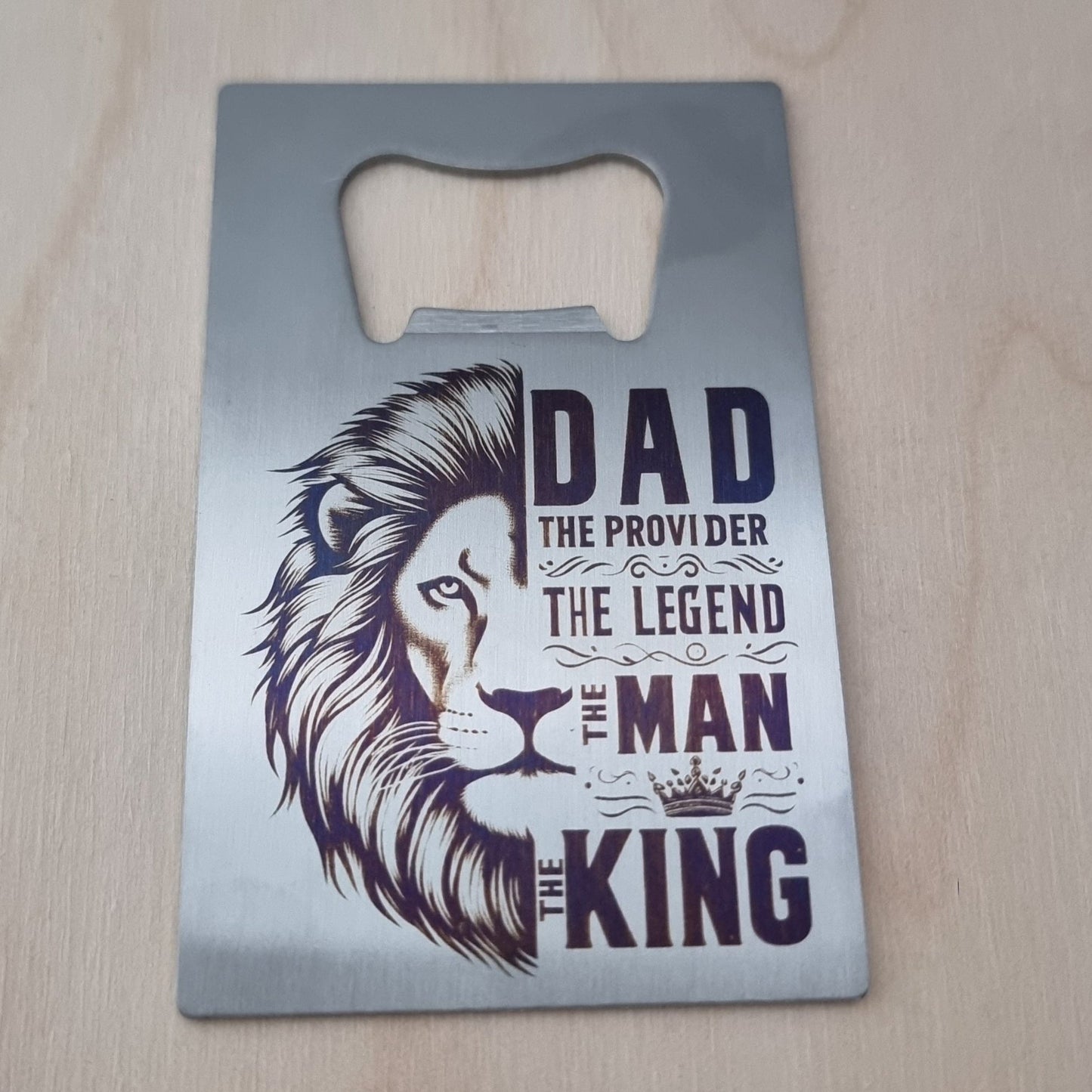 Metal bottle opener with lion design and text on a wooden surface