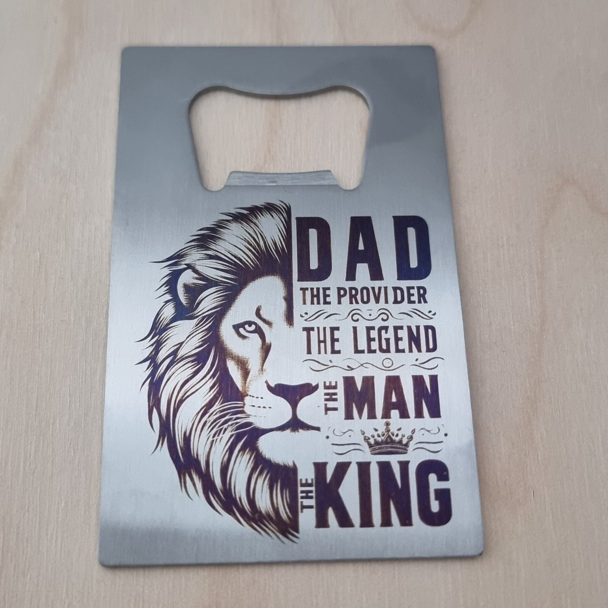 Metal bottle opener with lion design and text on a wooden surface