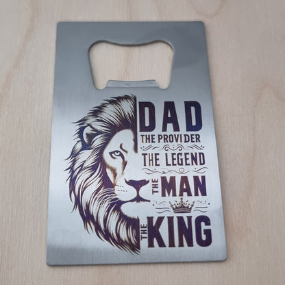 Metal bottle opener with lion design and text on a wooden surface