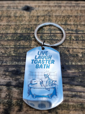 Stainless steel keyring with “Live Laugh Toaster Bath” engraving and skeleton in bathtub with toaster – dark humor goth keychain, funny emo aesthetic accessory