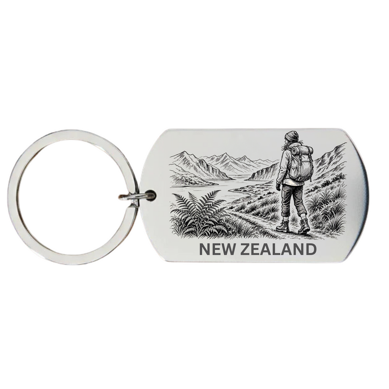 New Zealand backpacker keyring laser engraved stainless steel dog tag with female backpacker mountain peaks and native New Zealand wilderness scene on white background