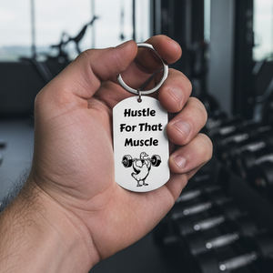 Keychain with 'Hustle For That Muscle' text and duck lifting weights illustration in a gym 