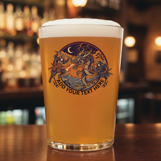 Personalised samurai dragon pint glass filled with beer on a bar counter, featuring two armoured samurai warriors battling a fire-breathing dragon under a crescent moon with custom text engraving