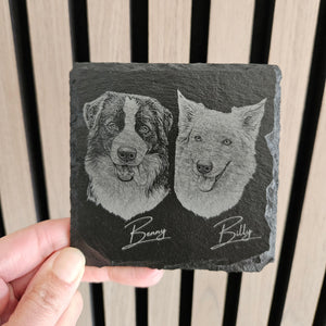 Slate coaster with engraved portraits of two dogs named Benny and Billy, held against a wooden background.