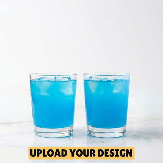 Two personalised 25ml shot glasses filled with blue cocktail on marble surface, unique custom printed party gift
