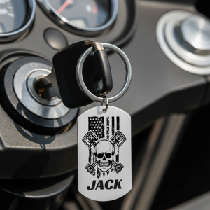Skull and crossbones dog tag keychain with pistons, American flag background, custom name on front, engraved message on back
