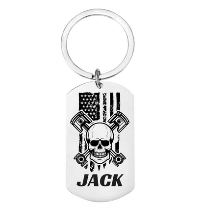 Skull and crossbones dog tag keychain with pistons, American flag background, custom name on front, engraved message on back
