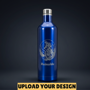 A metallic blue insulated bottle with a silver cap, featuring a silver graphic of a MTB cyclist and the name 'Reinaldo' printed on the front, set against a dark grey gradient background with an 'UPLOAD YOUR DESIGN' banner at the bottom.
