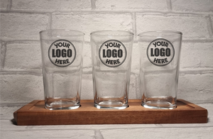 Close up of three custom printed personalised half pint glasses on wooden beer flight paddle, upload your own design gift