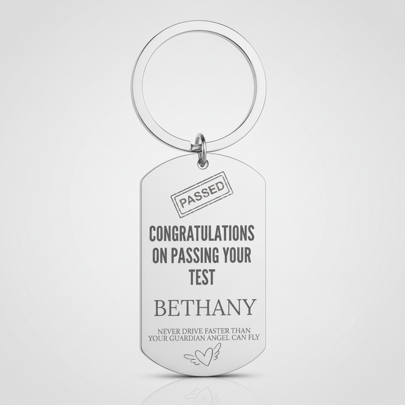 A silver metal dog tag keychain with a split key ring, featuring engraved personalized text that reads 'CONGRATULATIONS ON PASSING YOUR TEST BETHANY' and 'NEVER DRIVE FASTER THAN YOUR GUARDIAN ANGEL CAN FLY' on a light gray background.