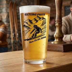 A pint of beer in a clear glass with a custom ski-themed graphic that reads 'GETTING PISTE' and 'Dan 25.01.