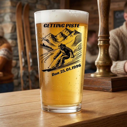 A pint of beer in a clear glass with a custom ski-themed graphic that reads 'GETTING PISTE' and 'Dan 25.01.