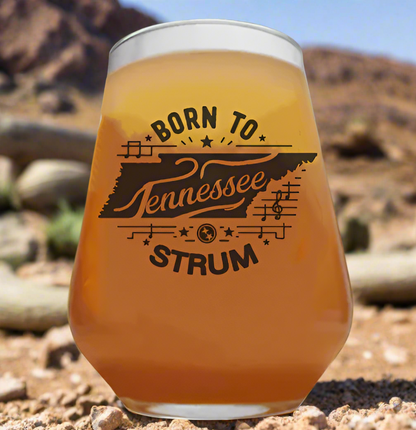 Monochrome line art of the Tennessee state outline with a music note inside and the phrase "Born to Strum" in western-style font, representing country music pride and Southern heritage.