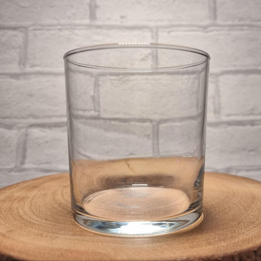 Plain 37cl Tubo tumbler glass on wooden slice before custom design is applied — short wide rocks glass shape with thick base and straight sides, white brick background
